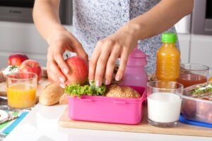 woman putting food in lunchbox